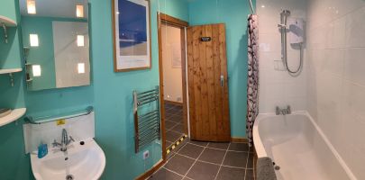 a bathroom with a sink, shower and towel rail